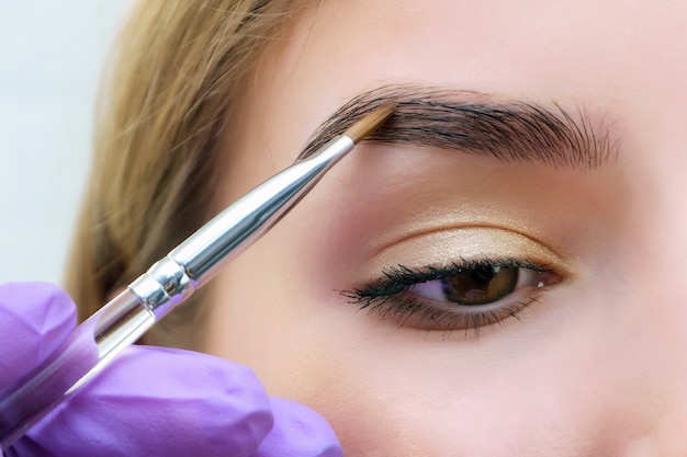 Young woman shaping eyebrows with brush, close up