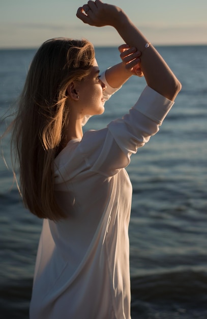 海辺に立っている若い女性が目を遮っている