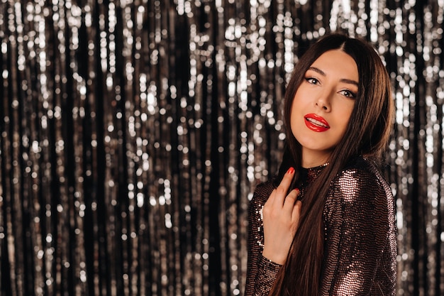 Foto una giovane donna con una giacca lucida su una tenda argentata