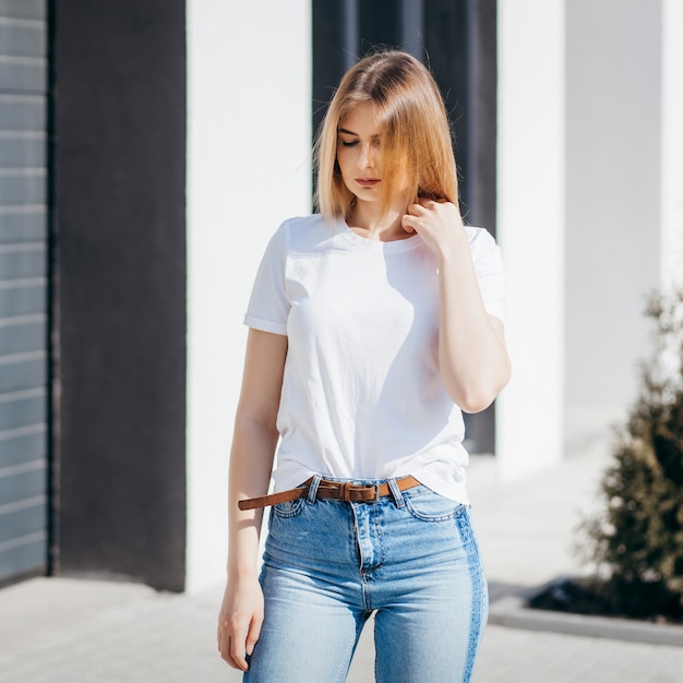 Young woman in shirt and jeans posing outdoors