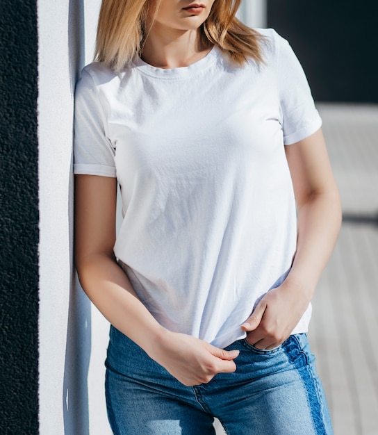 Young woman in shirt and jeans posing outdoors