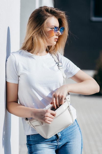 Young woman in shirt and jeans posing outdoors