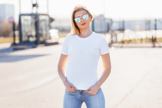 Молодая женщина в рубашке и джинсах представляя outdoors