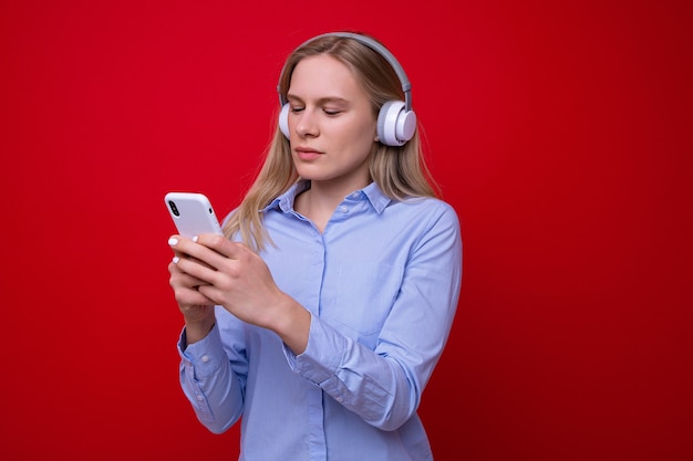 A young woman in a shirt listens to music from her phone