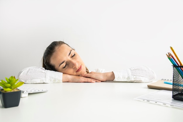 Giovane donna in una camicia che dorme sul posto di lavoro in ufficio