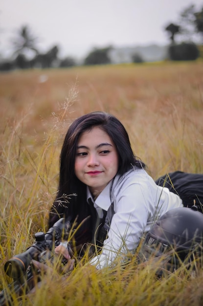 Young woman shooting rifle while lying on field