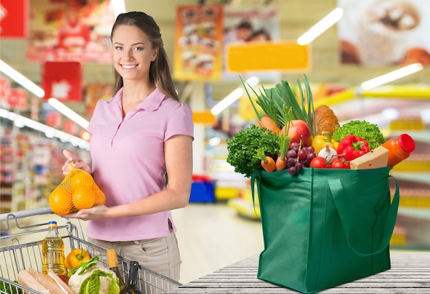 ぼやけた食料品の背景で買い物をする若い女性