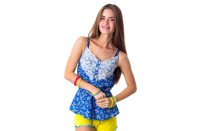 Молодая женщина в шортах и футболке с разноцветными браслетами стоит боком и смотрит в сторону