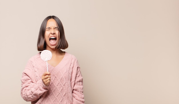 Young woman shouting aggressively, looking very angry, frustrated, outraged or annoyed, screaming no