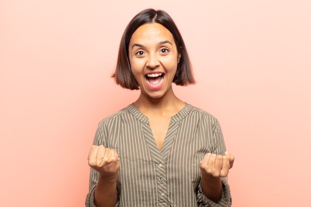 Young woman shouting triumphantly, laughing and feeling happy and excited while celebrating success