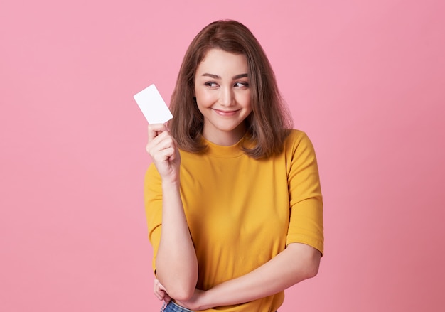 young woman showing credit card and looking isolated over pink