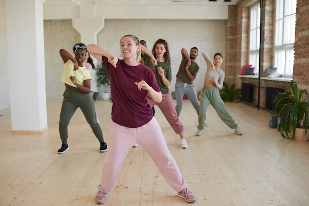 Фото Молодая женщина показывает танцевальные упражнения людям во время занятий в тренажерном зале