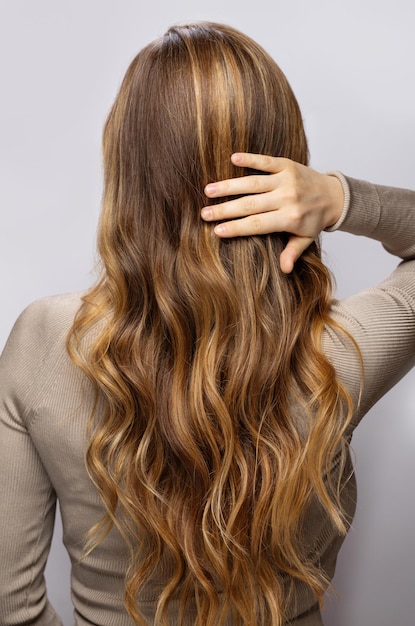 Young woman showing her beautiful hair after dyeing and styling in a professional salon