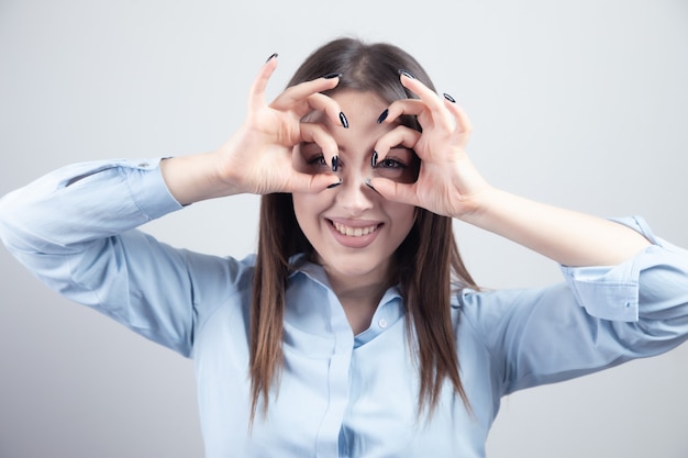 young woman showing okay sign over eyes