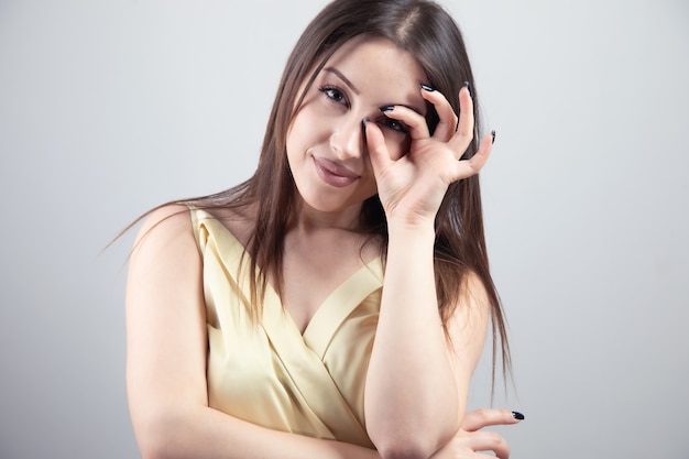 目の上に大丈夫サインを示す若い女性