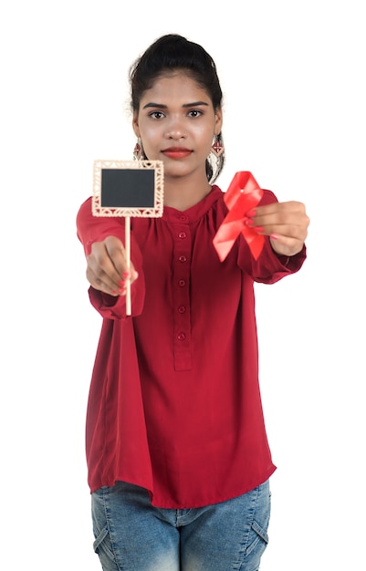 Young woman showing red ribbon HIV, AIDS awareness ribbon, healthcare and medicine concept