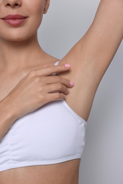 Young woman showing smooth skin after epilation on white background closeup