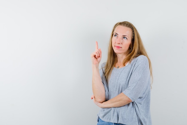 Young woman showing up with her finger on white background