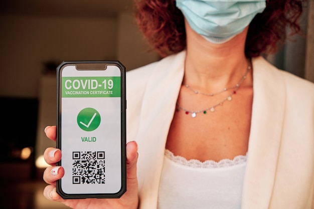 Foto giovane donna che mostra il passaporto sanitario per la vaccinazione su smartphone con codice qr per il turismo - covid-19