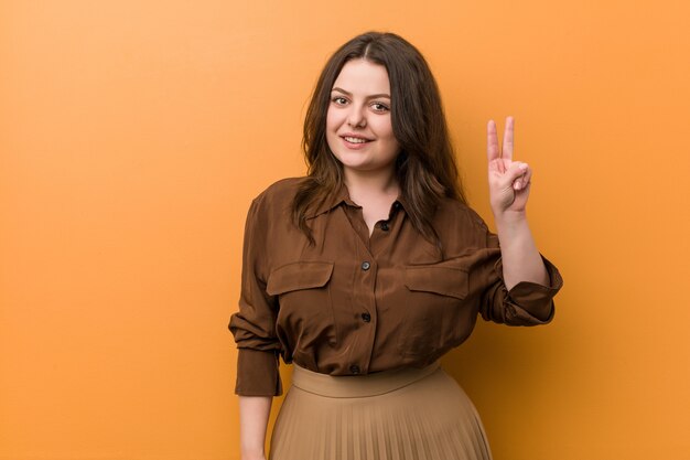 Young woman showing victory sign and smiling broadly