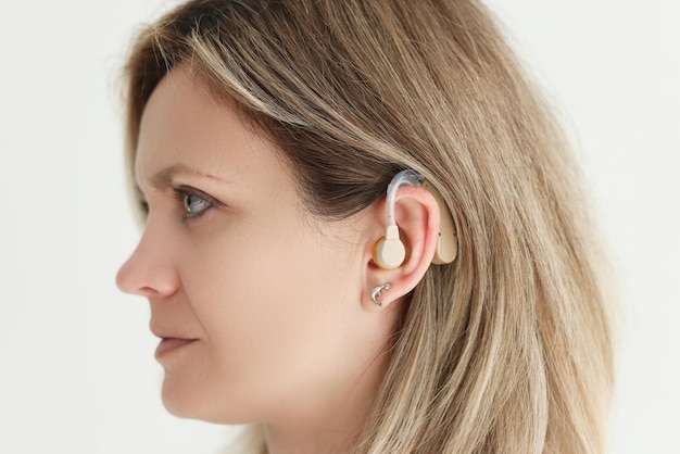 Young woman shows hearing aid in ear female with hearing disease uses modern medical equipment