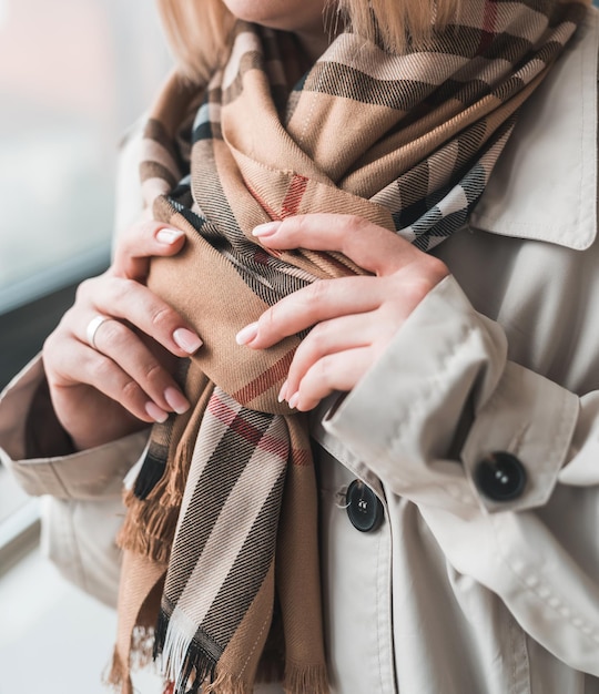 Young woman shows off a beautiful autumn stylish scarf and coat. Autumn style concept