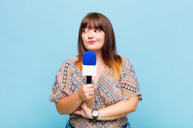 Young woman shrugging, feeling confused and uncertain, doubting with arms crossed and puzzled look