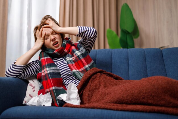 Photo young woman sick with flu virus suffering from severe headache while lying on couch