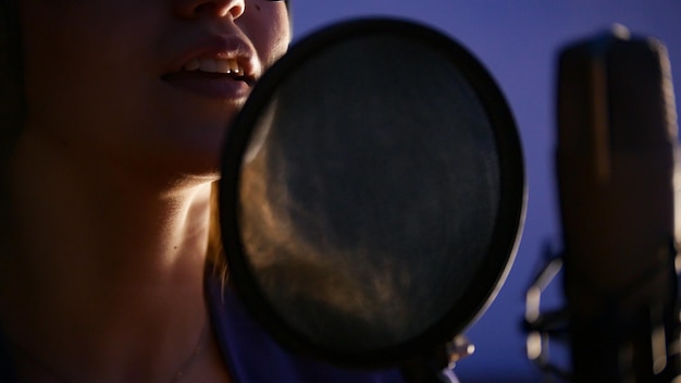 A young woman singing through the popfilter