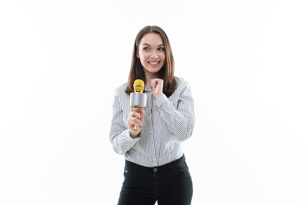 Young woman sings into a microphone on a white background