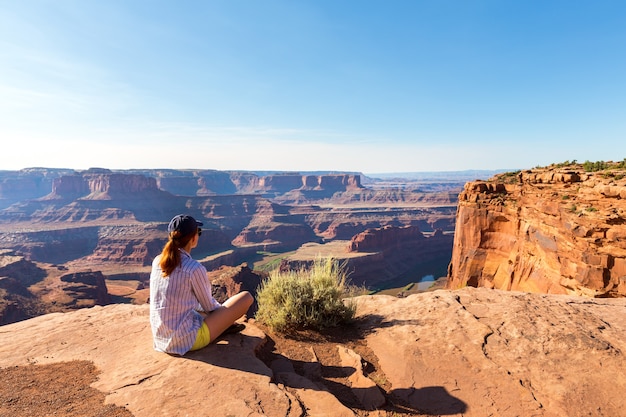 Young woman siting on the top of rocky mountain in valley