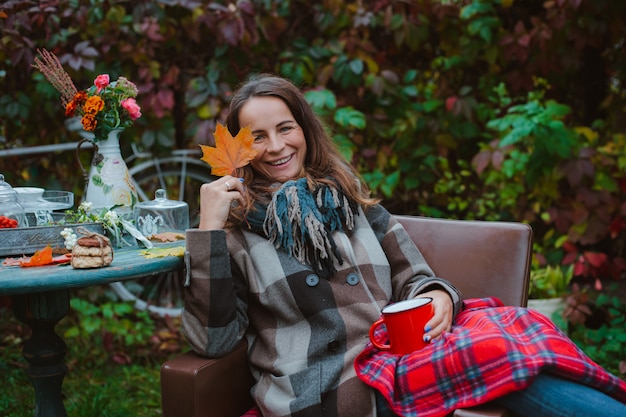 Young woman sits chair outside with coffee mug