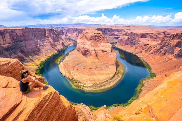 A young woman sits looking at Horseshoe Bend and the Colorado River in the background, Arizona. U.S