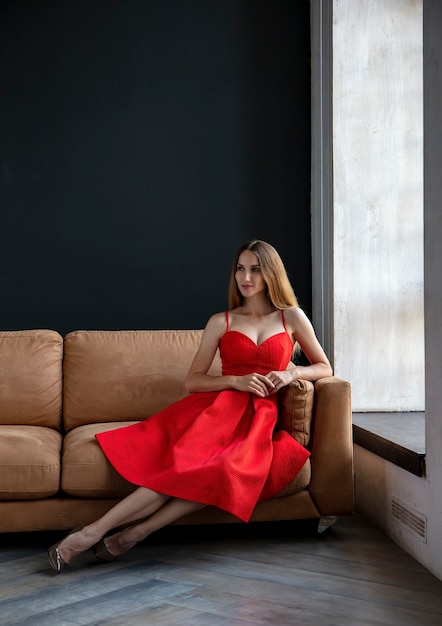 young woman sits on the sofa and looks out the window portrait of a beautiful girl