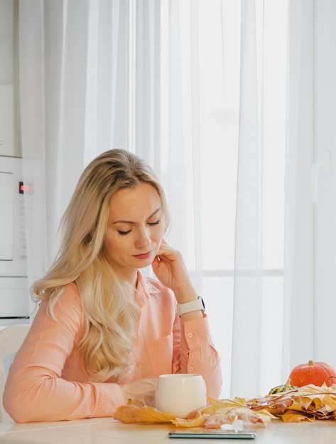 A young woman sits at a table and drinks coffee from a cup