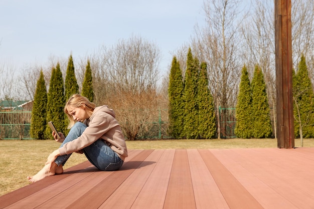 A young woman sits on a terrace in the yard early spring