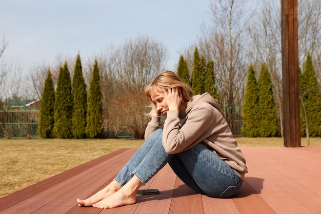 A young woman sits on a terrace in the yard early spring