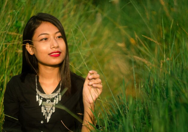 Photo young woman sitting amidst grass