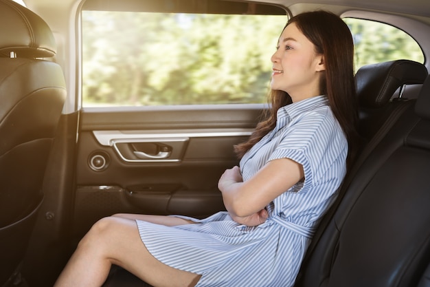 Young woman sitting at the back seat of car