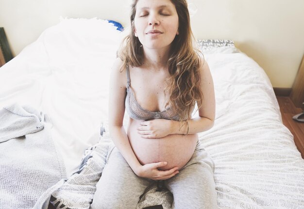 Foto giovane donna seduta a letto a casa