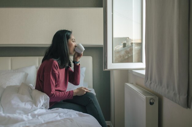 家でベッドに座っている若い女性