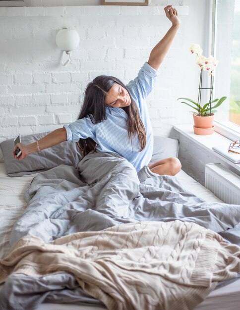 Foto giovane donna seduta a letto a casa