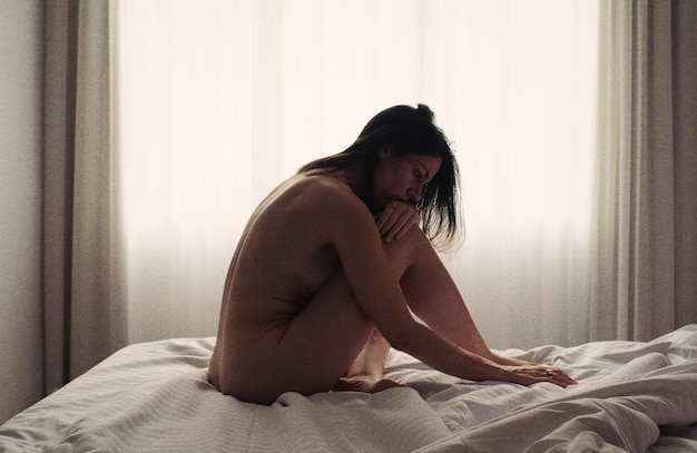 Foto giovane donna seduta a letto a casa