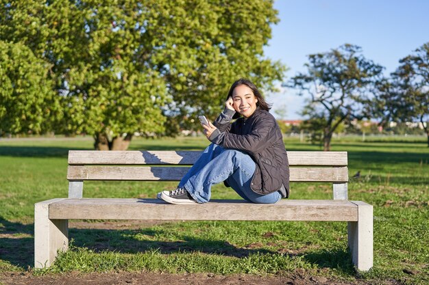 Photo young woman sitting on bench against trees