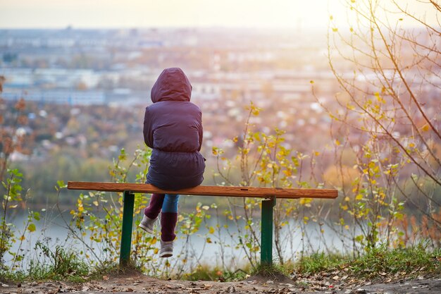 Photo young woman sitting on bench in autumn city park