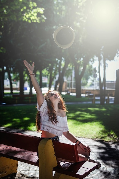 Foto giovane donna seduta su una panchina al parco durante una giornata di sole