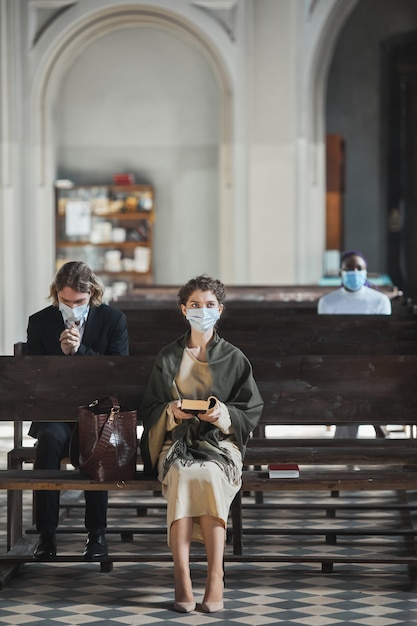 Foto giovane donna seduta su una panchina che legge la bibbia durante la messa