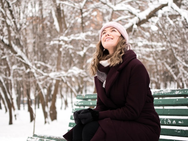 young woman sitting on bench during winter
