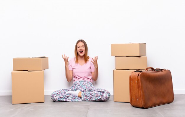 young woman sitting between boxes furiously screaming