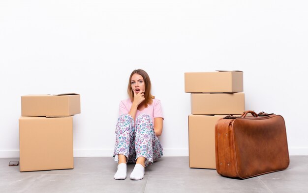 young woman sitting between boxes surprised